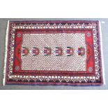 A cream ground rug with double border, populated with stylised foliage,