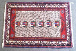 A cream ground rug with double border, populated with stylised foliage,