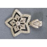 A white metal flower star pendant grain set with round brilliant cut diamonds. Stamped 18K 750.