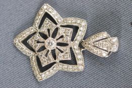 A white metal flower star pendant grain set with round brilliant cut diamonds. Stamped 18K 750.