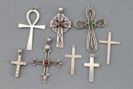 A collection of eight silver cross pendants of variable designs.