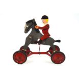 A child's pull along huntsman toy, with articulated wooden limbs and supported on four wheels,