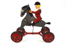 A child's pull along huntsman toy, with articulated wooden limbs and supported on four wheels,