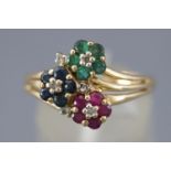 A yellow metal dress ring having three crossover flowers set with emeralds....