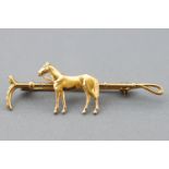 A yellow metal horse and stirrup bar brooch. No hallmark - tests indicated gold plated base metal.