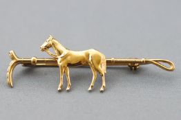 A yellow metal horse and stirrup bar brooch. No hallmark - tests indicated gold plated base metal.