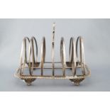 A silver toast rack with foliate strap handle over oval form separators on a gadrooned base