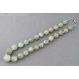 A single strand of graduated polished green beads, strung knotted with a gold plated screw clasp.