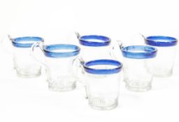 A set of six hand-blown glass punch cups, with blue rims and applied handles,