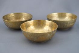 Three Mughal stye brass bowls engraved with bands of script to the interiors,