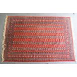 An Afghan rug with geometric medallions on a red ground, surrounded by a wide border,