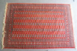 An Afghan rug with geometric medallions on a red ground, surrounded by a wide border,