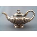 A silver squat form melon shaped teapot with fluted lid set with a cast floral and foliate handle