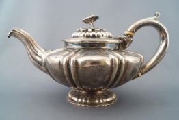 A silver squat form melon shaped teapot with fluted lid set with a cast floral and foliate handle