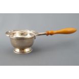 A silver tea strainer and stand, set with a wooden handle,