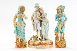 A pair of Continental bisque figurines and a figural group polychrome decorated in turquoise and