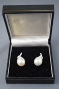 A white metal pair of drop earrings,