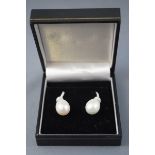 A white metal pair of drop earrings,