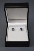 A white metal pair of single stone stud earrings, each set with a oval faceted cut blue kyanite.