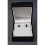 A white metal pair of single stone stud earrings, each set with a oval faceted cut blue kyanite.