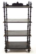 A Victorian four tier ebonised what not with shaped crest and turned uprights,