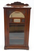 A late 19th century mahogany music cabinet with mirror panels above a glazed door,