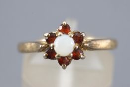 A yellow metal cluster ring set with garnets and opal. Stamped Silver & GP. Size: N