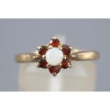 A yellow metal cluster ring set with garnets and opal. Stamped Silver & GP. Size: N