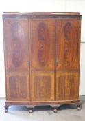 A mahogany triple wardrobe with blind fretwork crest on cabriole legs with ball and claw feet,