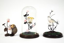 Two Royal Worcester figures of birds on metal flowering branches under glass domes....