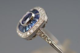 A white metal cluster ring set with a central oval faceted cut sapphire