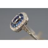 A white metal cluster ring set with a central oval faceted cut sapphire