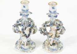 A pair of 19th century German porcelain candlesticks, decorated with figures in blue and white,