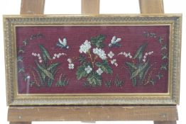 A framed beadwork picture of insects, white flowers and foliage on a red ground,