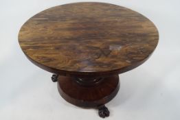 A William IV Goncalo Alves circular centre table on baluster pedestal with three carved lion paw