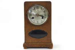 A 1930's oak cased mantel clock, with silvered dials, striking on a gong with pendulum and key,