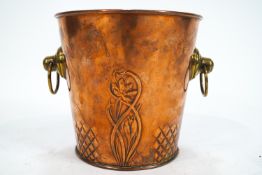 A copper ice bucket with brass ring handles embossed with flowers in Art Nouveau style,