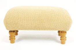 A contemporary upholstered footstool of rectangular form raised on four baluster turned oak legs,