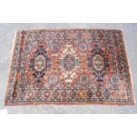 A Middle Eastern rug with multiple medallions on a terracotta field within three borders,