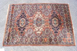 A Middle Eastern rug with multiple medallions on a terracotta field within three borders,