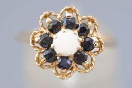 A yellow metal floral design cluster ring set with a central round cabochon opal