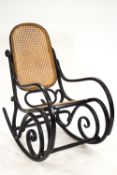An ebonised bent wood rocking chair with a bergere back and seat,