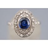 A white metal cluster ring set with a central deep blue sapphire