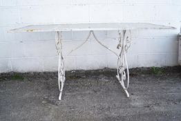 A wrought iron metal garden table with a ripple glass top,