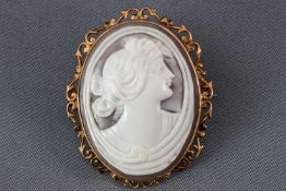 A yellow metal oval carved cameo brooch with scroll and leaf design mount. Stamped 9ct.