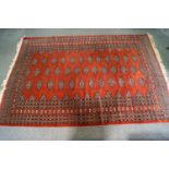 A large Berber style carpet of rust colour, the centre with lozenge motifs in a stylised border,