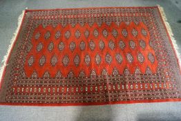 A large Berber style carpet of rust colour, the centre with lozenge motifs in a stylised border,