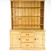 A pine dresser with raised back and three drawers flanked by two panelled cupboard doors,