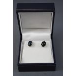 A white metal pair of single stone stud earrings,
