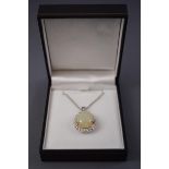 A white metal cluster pendant set with a pear cabochon cut opal